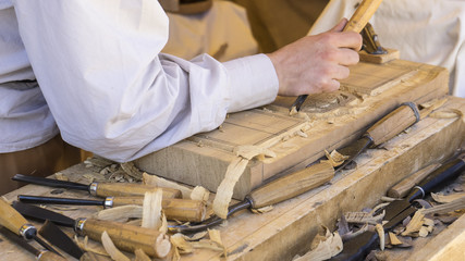 craftsman carving wood in a medieval fair, carpentry tools