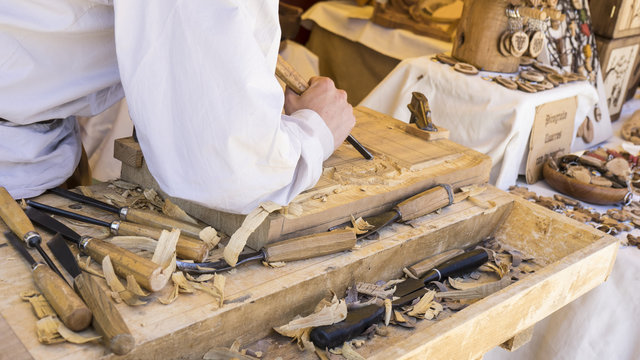 Carpenter, craftsman carving wood in a medieval fair, carpentry
