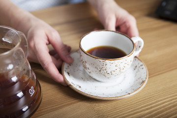 White cup of coffee in hand. Barista holding coffee