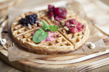 Plate of belgian waffles with ice cream, sauce and fresh berries
