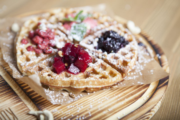 Belgian waffles with fresh berries on rustic wooden background