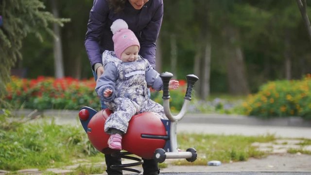Happy family: Father, Mother and child - little girl walking in autumn park: mammy and baby playing at playground