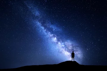 Fototapeten Milchstraße. Schöner Nachthimmel mit Sternen und Silhouette eines alleinstehenden Mannes auf dem Berg. Blaue Milchstraße mit Mann auf dem Hügel. Hintergrund mit Galaxie und Silhouette eines Mannes. Universum © den-belitsky