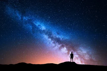 Poster Melkweg. Mooie nachtelijke hemel met sterren en silhouet van een alleenstaande man op de berg. Melkweg met rood licht en man op de heuvel. Achtergrond met melkweg en silhouet van een man. Universum © den-belitsky