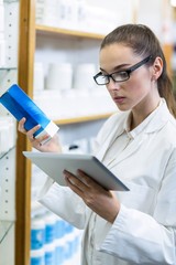 Pharmacist using digital tablet while checking medicine