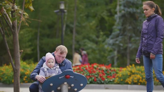 Happy family: Father, Mother and child - little girl walking in autumn park: mamy, dad and baby playing at playground