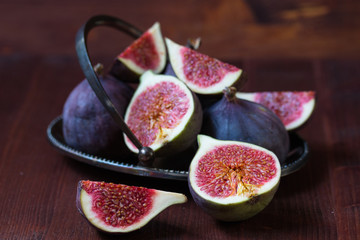 Whole and sliced figs on the dark wooden background. Selective focus.