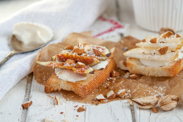 Fototapeta na wymiar Bruschetta with goat cheese, pear and almond nuts on parchment