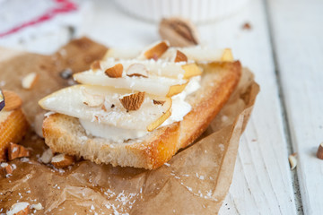Bruschetta with goat cheese, pear and almond nuts on parchment