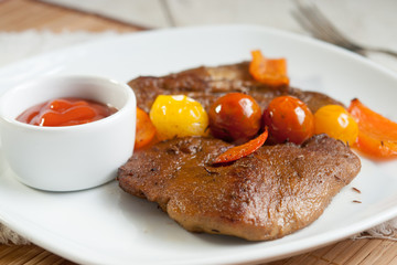 Vegetarian steak made from vegan meat seitan, with cherry tomatoes