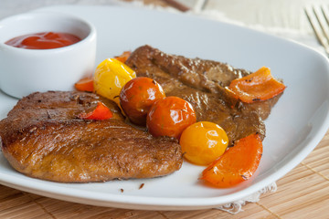 Vegetarian steak made from vegan meat seitan, with cherry tomatoes