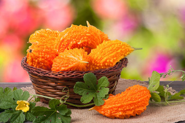 bitter melon or momordica in a wicker basket on wooden table with blurred background