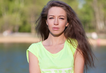 Beautiful Fitness the model in a Top Costs on the bank of the Lake in the Summer on a sunset. Blowing Long Hair