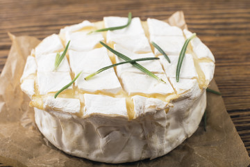 Camembert with rosemary on a wooden board - obrazy, fototapety, plakaty