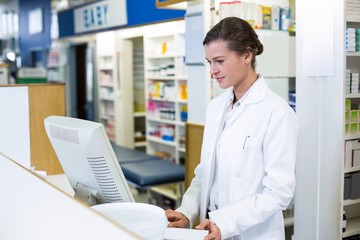 Pharmacist making prescription record through computer - Powered by Adobe