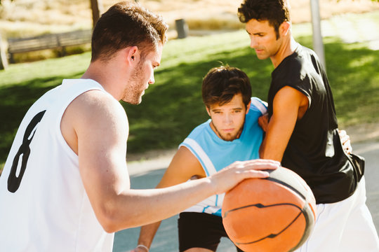Portrait of group of friends playing basketball on court.