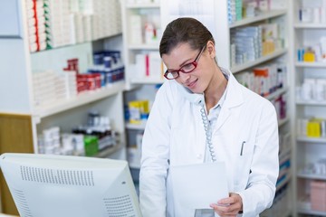 Pharmacist holding prescription paper while talking on phone