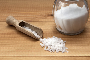 salt crystals with wooden scoop and salt shaker on wooden table