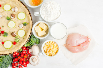 The selection of ingredients for the preparation of traditional French dishes quiche lorraine, on white wooden table with a baked dough in the baking dish in the cooking process, top view, copy space