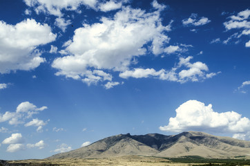 Mount Aragats in the autumn sunny day against the blue sky covered by clouds
