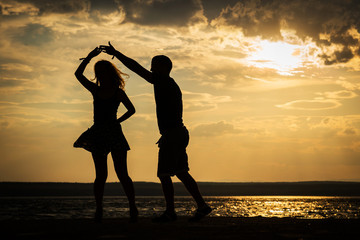 Couple dancing at sunset salsa / brazilian zouk. Lovers, dance partners spinning, latin festival dance concept. - obrazy, fototapety, plakaty