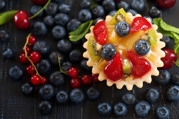 mix of fresh berries and  cheesecake on rustic dark grey wooden desk