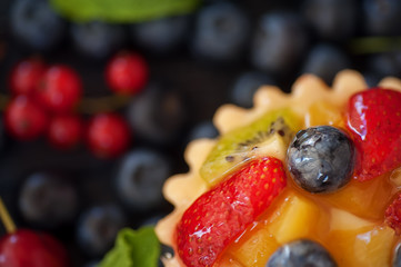 mix of fresh berries and  cheesecake on rustic dark grey wooden desk