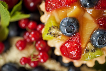 Fototapeta na wymiar mix of fresh berries and cheesecake on rustic dark grey wooden desk
