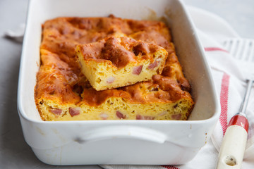 Pie with cheese and ham in baking dish.