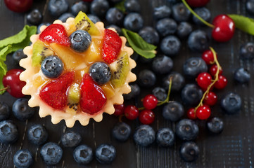 mix of fresh berries and  cheesecake on rustic dark grey wooden desk