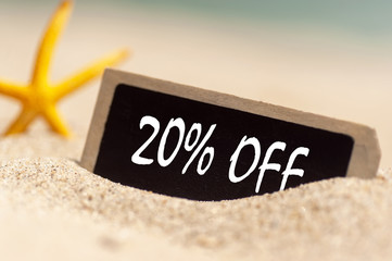 wooden board on sunny sandy beach  with text 20% off