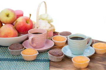 Still life of pink and blue coffee cups, cupcakes, apples