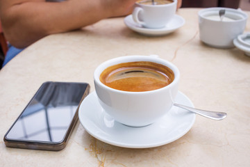 Smartphone and cup of coffee on marble table