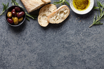 Italian food background with ciabatta bread, olive oil, olives and rosemary
