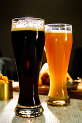 Two glasses of beer standing on the table on a dark background c