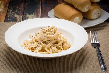 Fettuccine Alfredo classic Italian Pasta on a dark wood table..