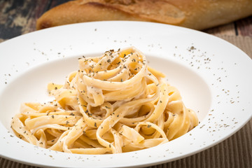 Fettuccine Alfredo classic Italian Pasta on a dark wood table..