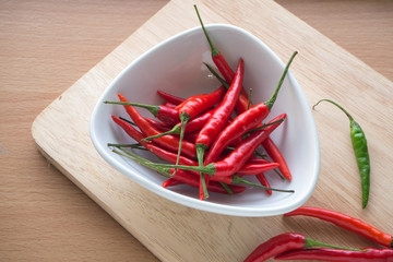 Ripe pepper on the white dish and wooden block.