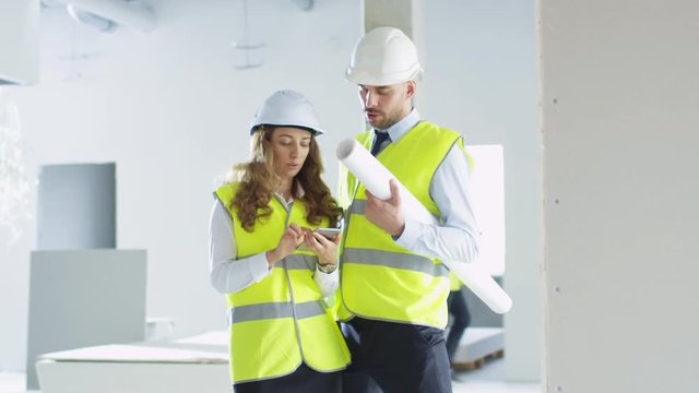 Male and Female Engineers in Hard Hats Having Conversation inside a Building under Construction. Shot on RED Cinema Camera in 4K (UHD).