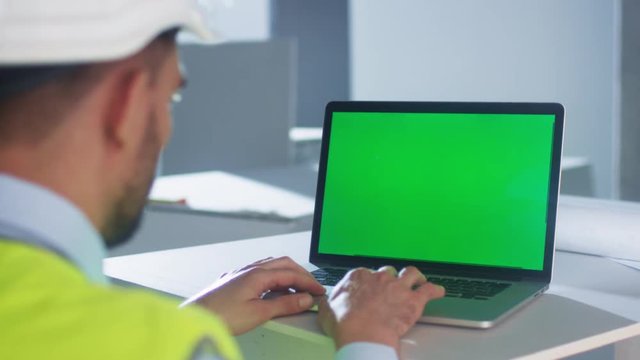 Engineer using Laptop Computer with Green Screen inside Building Under Construction. Great for Mockup usage. Shot on RED Cinema Camera in 4K (UHD).