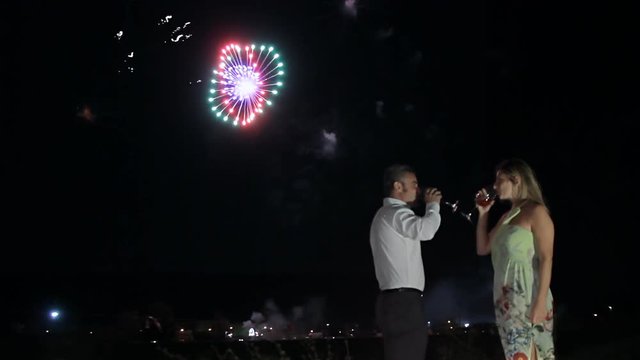 mature couple celebrating anniversary drinking wine and looking at fireworks show  hugging together
