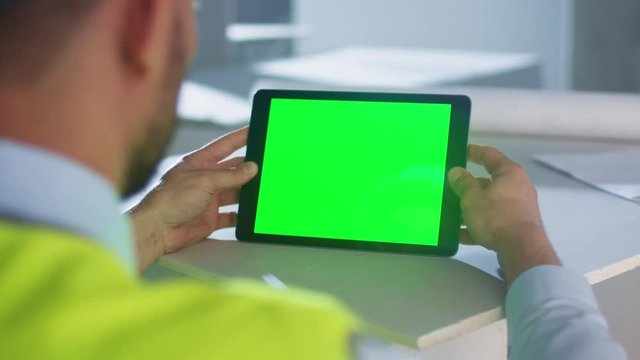 Engineer Holding Tablet Computer with Green Screen inside Building Under Construction. Great for Mockup usage. Shot on RED Cinema Camera in 4K (UHD).