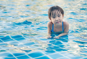 Fototapeta na wymiar Asian girl is playing in the pool, laying down