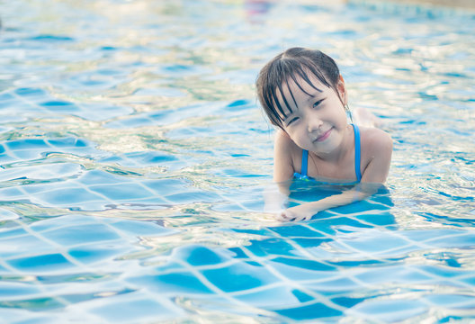 Asian girl is playing in the pool, laying down