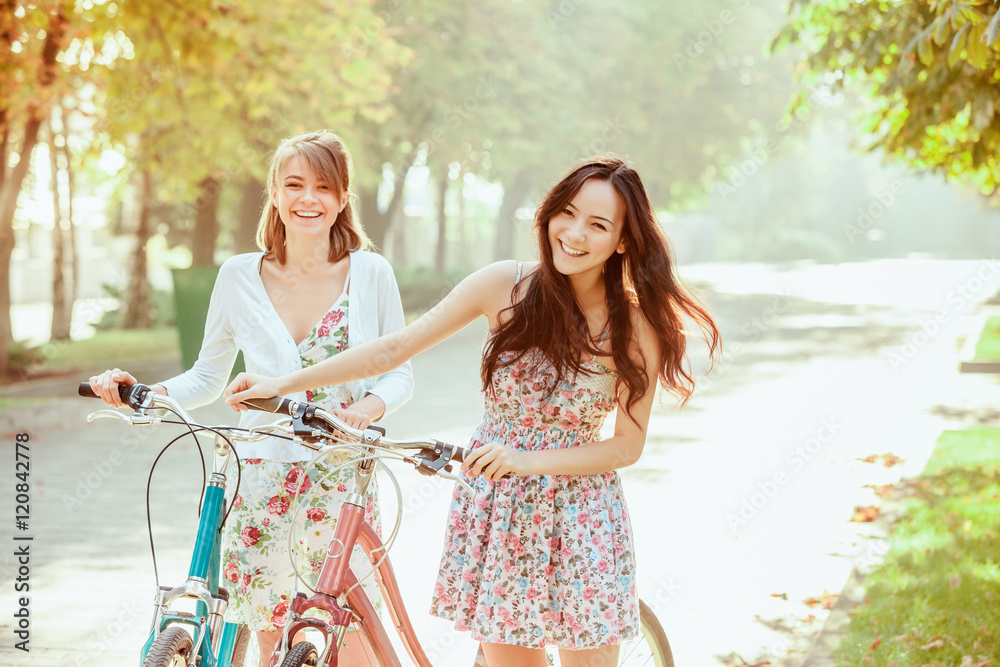 Wall mural The two young girls with bicycles in park