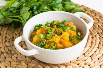 Stewed pumpkin and potatoes with parsley in white soucepan