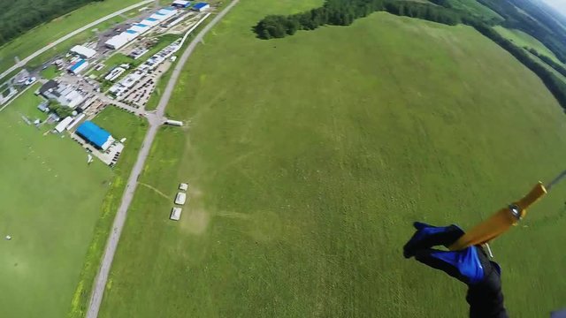Skydiver girl parachuting in sky above green fields. Landscape. Extreme sport. Sunny