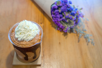 Frappuccino coffee with whipped cream on a wooden table decorated with dried flower, Selective focus