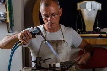 Goldsmith melting and casting metal with blowtorch