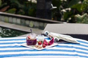 Healthy breakfast, smoothie with  granola and yogurt near the pool © nadingrinko